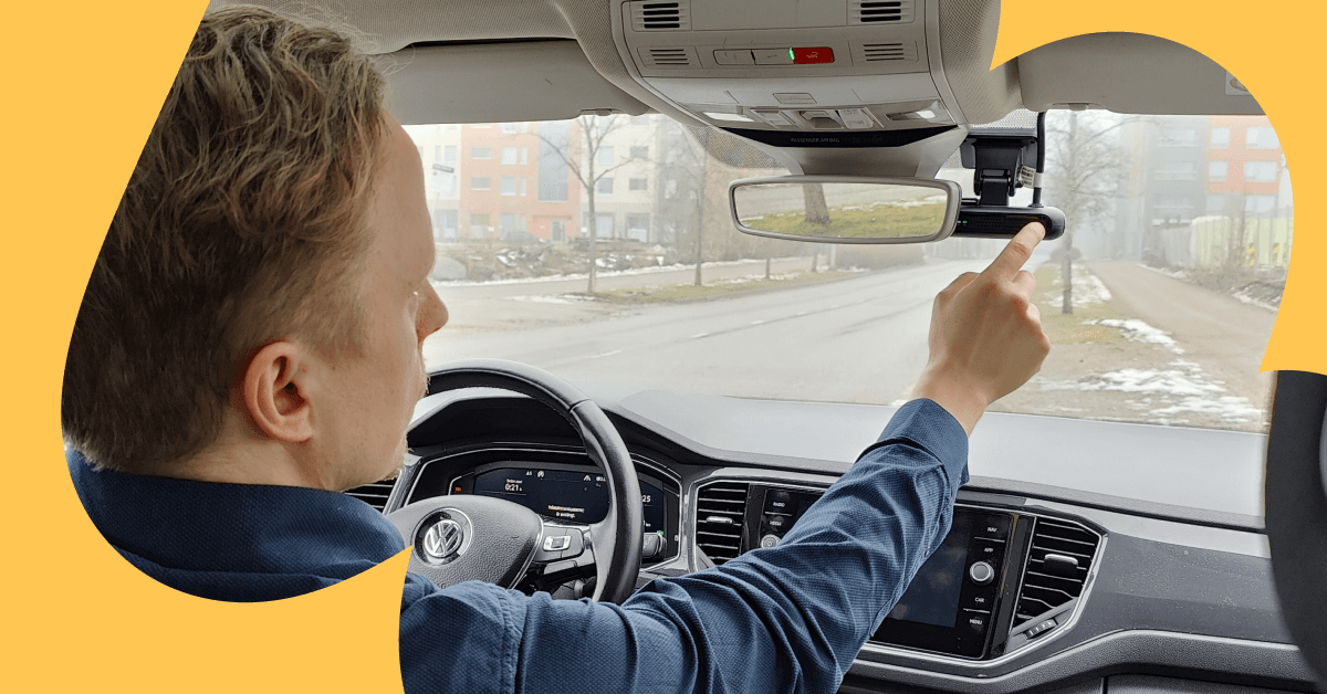 Et udsyn fra passagersædet fremad, hvor en chauffør tænder for et dashcam, der er fastgjort til forruden.
