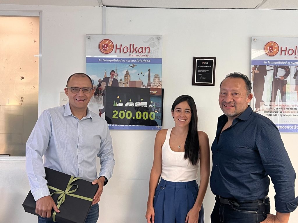 One female Mapon employee standing between two male Holkan representatives in their office in Mexico.