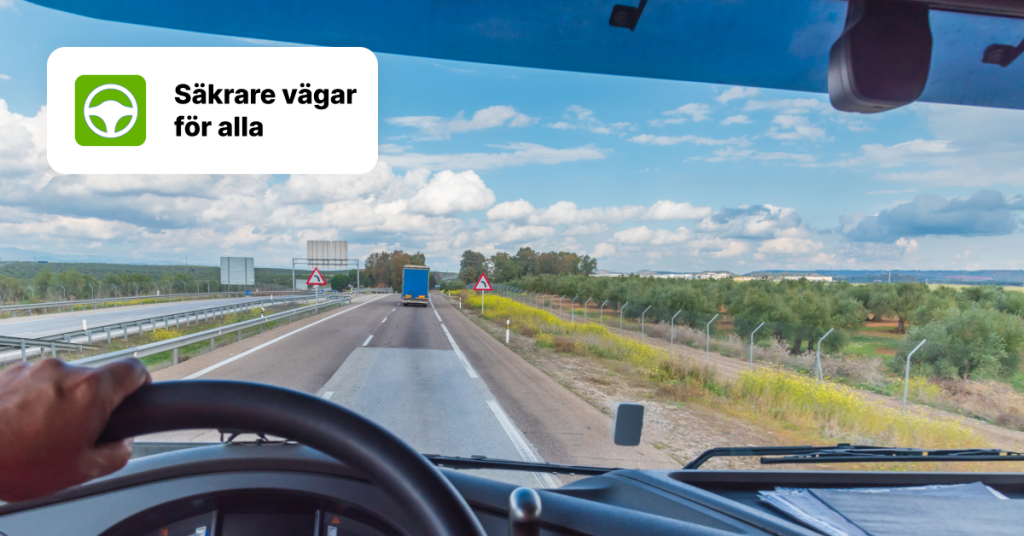 Vy från en lastbilsförares perspektiv på en motorväg med budskapet "Säkrare vägar för alla", som betonar vikten av säker körning.