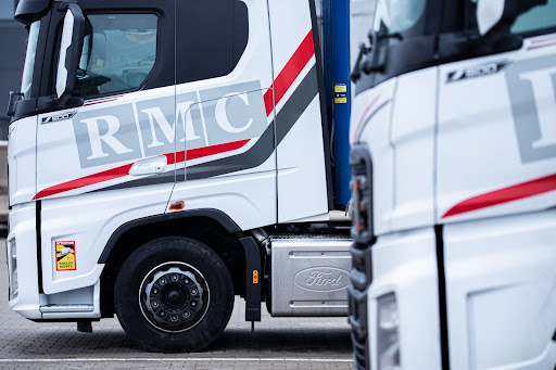 Nærbillede af RMC-Transports lastbiler parkeret side om side med fokus på branding og køretøjsdetaljer.