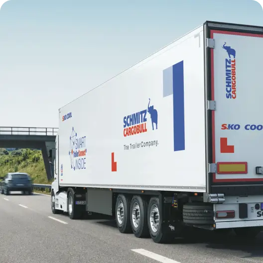 A white Schmitz Cargobull trailer being hauled on a highway.